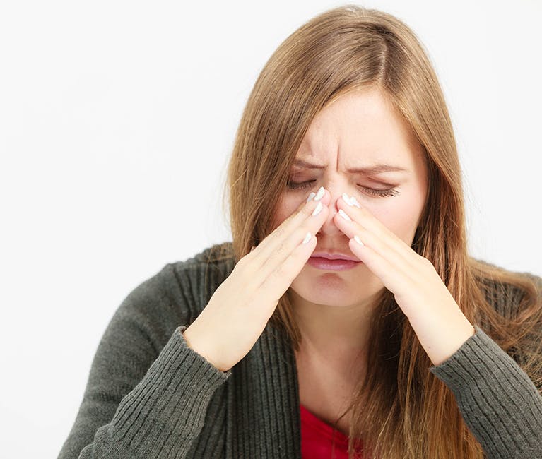 521788762 Woman dressed in winter clothing blowing her nose