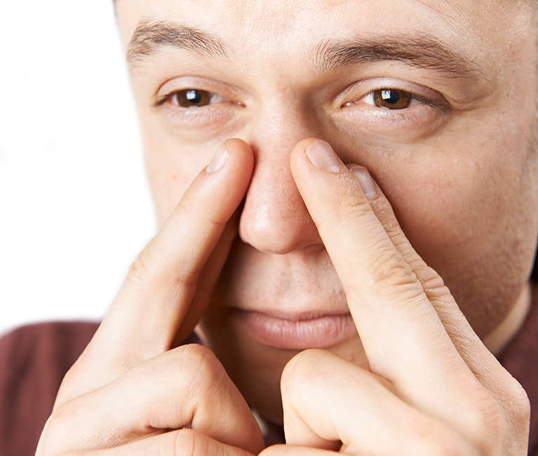 Man suffering nasal congestion massages his sinuses
