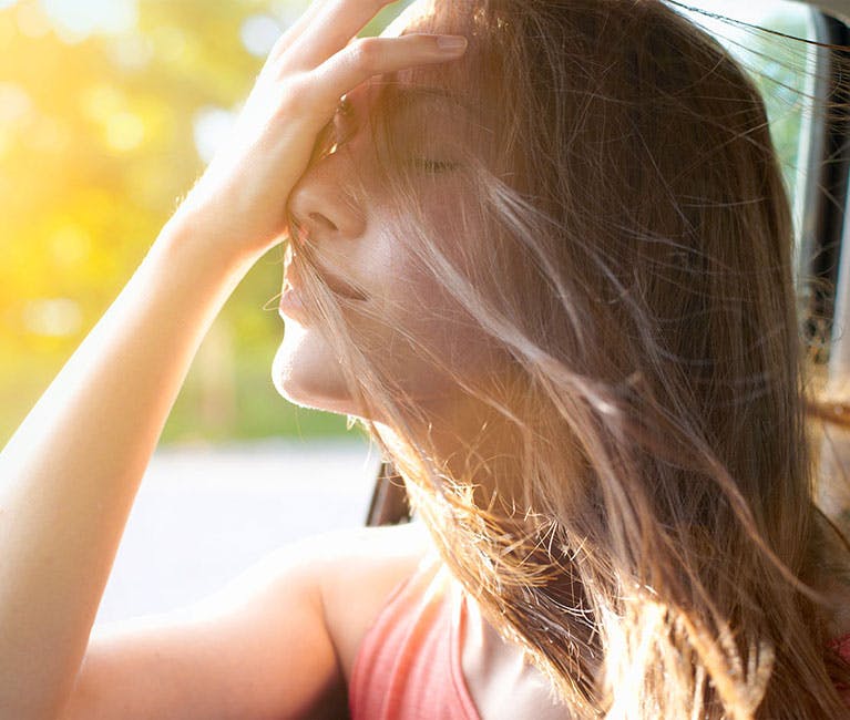 Otrivin-Wie-Nasensprays-helfen-können Frau in Auto streckt ihren Kopf aus dem Fenster und streicht sich die Haare aus dem Gesicht