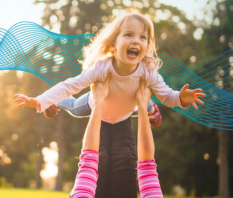 So werden Kinder schnell wieder fit Erkältung bei Kindern: Mutter liegt auf dem Rasen und hält ihre Tochter in die Luft
