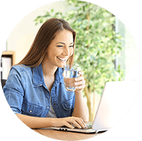 Woman drinking water and looking at her laptop