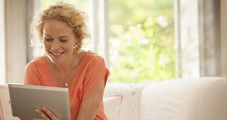 Women using an iPad while sitting on a couch Women using an iPad while sitting on a couch