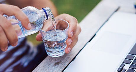 Bottle of water being poured into a glass Bottle of water being poured into a glass