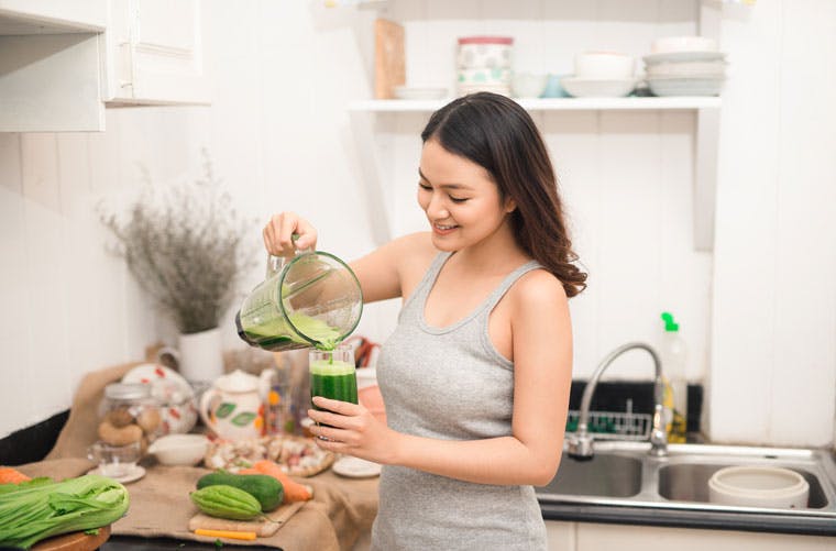631505351 Woman pouring green smoothie into a glass