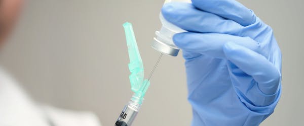 Female doctor filling a vaccine syringe.