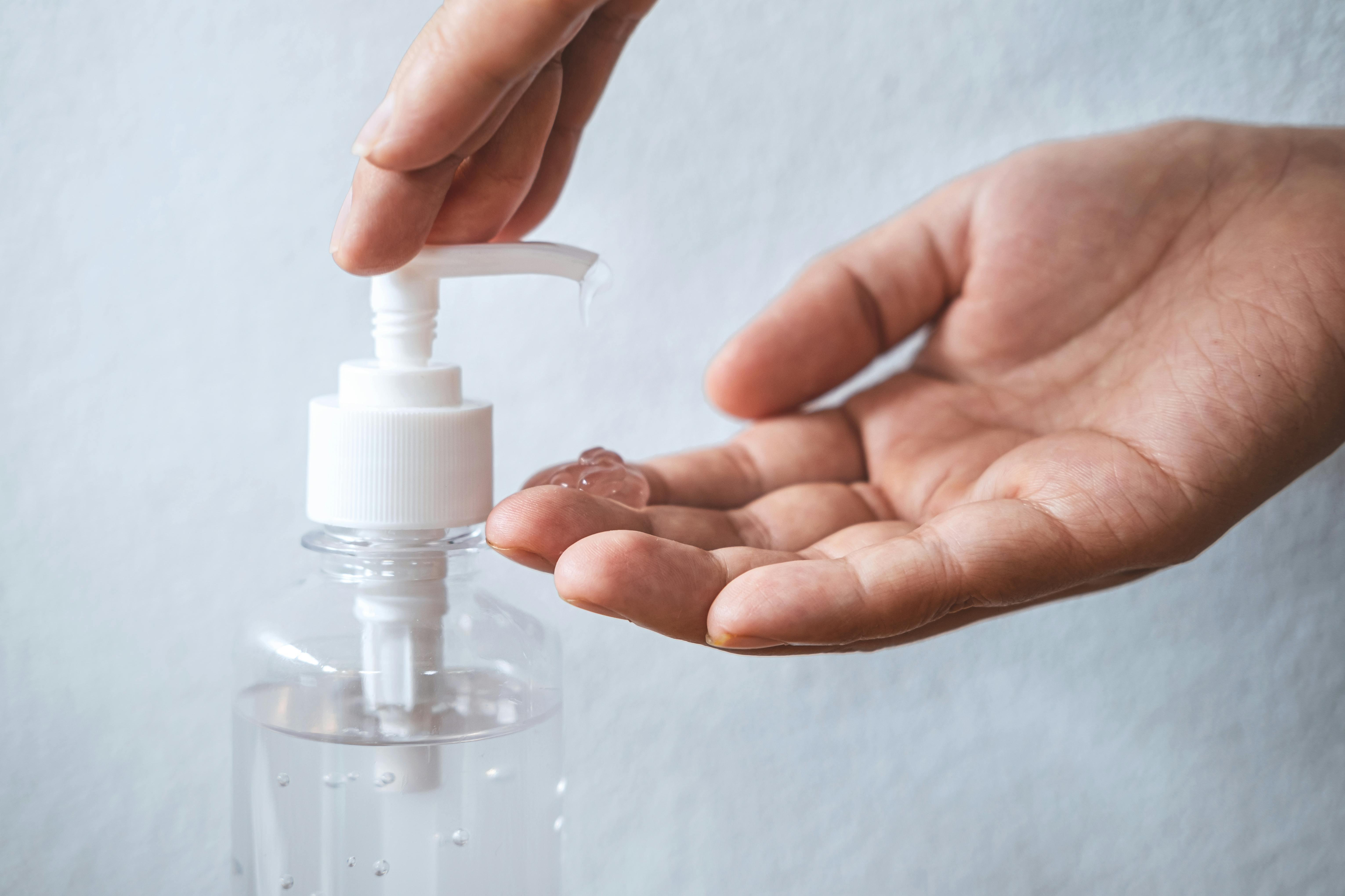 Person disinfecting hands with clear hand sanitizer gel Person disinfecting hands with clear hand sanitizer gel