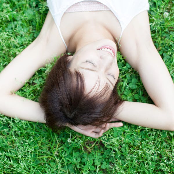 Young woman lying in the grass enjoying the sun.