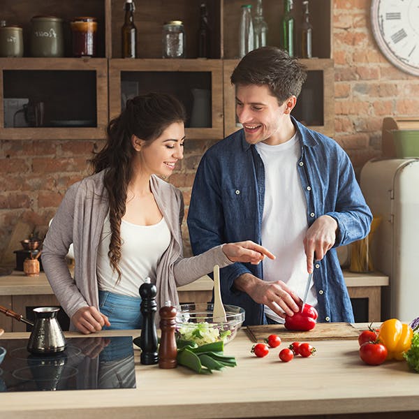 Couple cooking food together on purple background Couple cooking food together on purple background