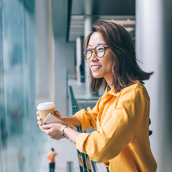 Smiling woman holding a coffee cup looking outside Smiling woman holding a coffee cup looking outside