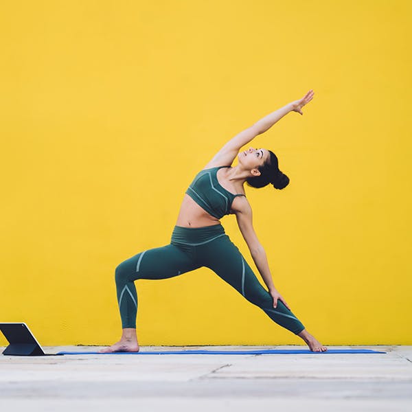 Woman doing yoga stretches in exercises clothes on a yellow background Woman doing yoga stretches in exercises clothes on a yellow background