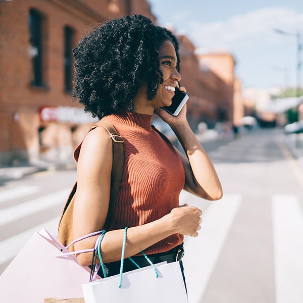 Woman walking across the street on the phone with shopping bags Woman walking across the street on the phone with shopping bags