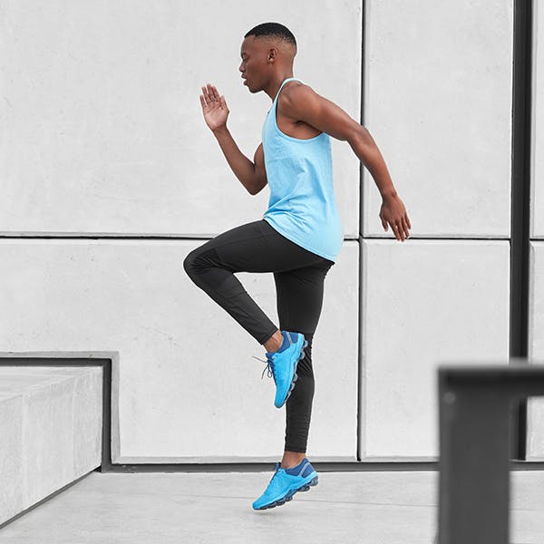 Young man doing high knee exercises in workout clothes Young man doing high knee exercises in workout clothes