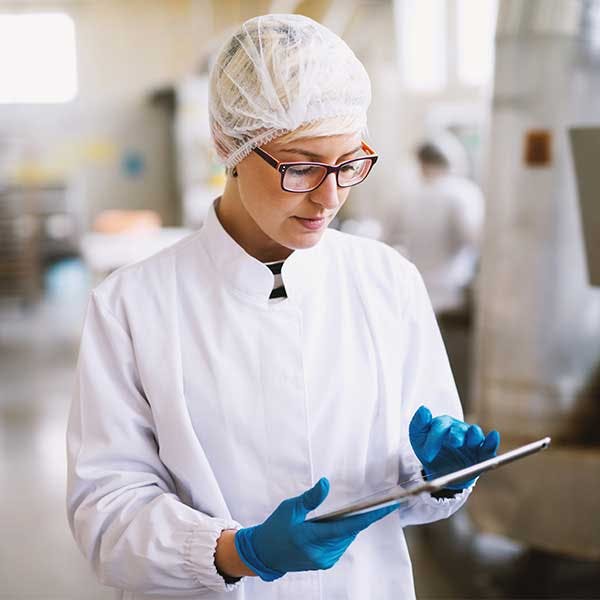 Mujer con traje protector mirando una tableta en el laboratorio Mujer con traje protector mirando una tableta en el laboratorio