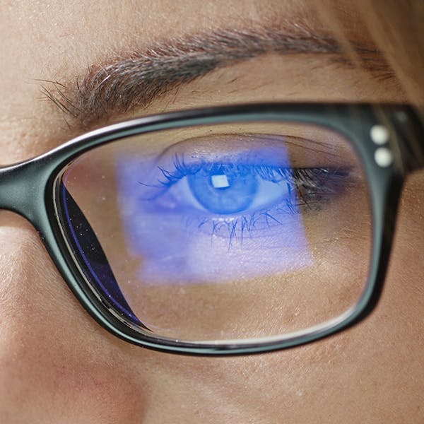 Close up of someone’s eye and glasses with computer screen glare Close up of someone’s eye and glasses with computer screen glare
