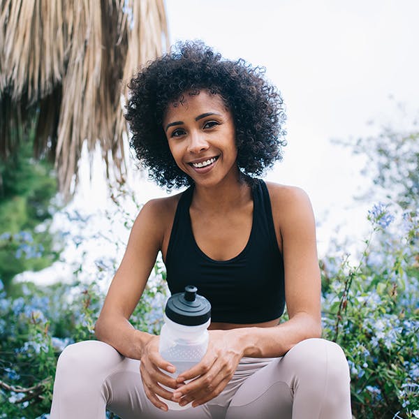 Woman sitting holding a water bottle outside Woman sitting holding a water bottle outside