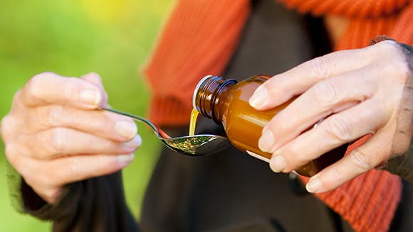Femme qui prend une cuillère de sirop contre le rhume et la grippe Femme qui prend une cuillère de sirop contre le rhume et la grippe