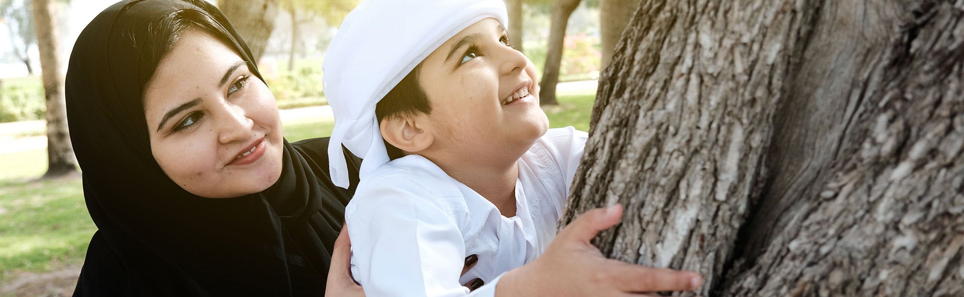 أم تمسك ابنها وهو يتسلّق شجرة أم تمسك ابنها وهو يتسلّق شجرة
