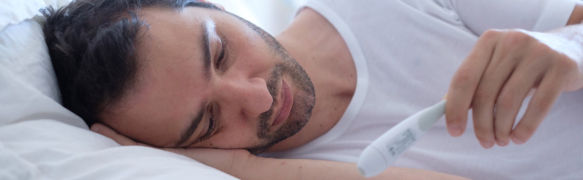A man in a bed suffering from fever A man in a bed suffering from fever