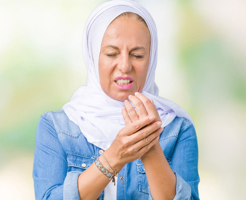 A woman experiencing bone pain in her hand A woman experiencing bone pain in her hand