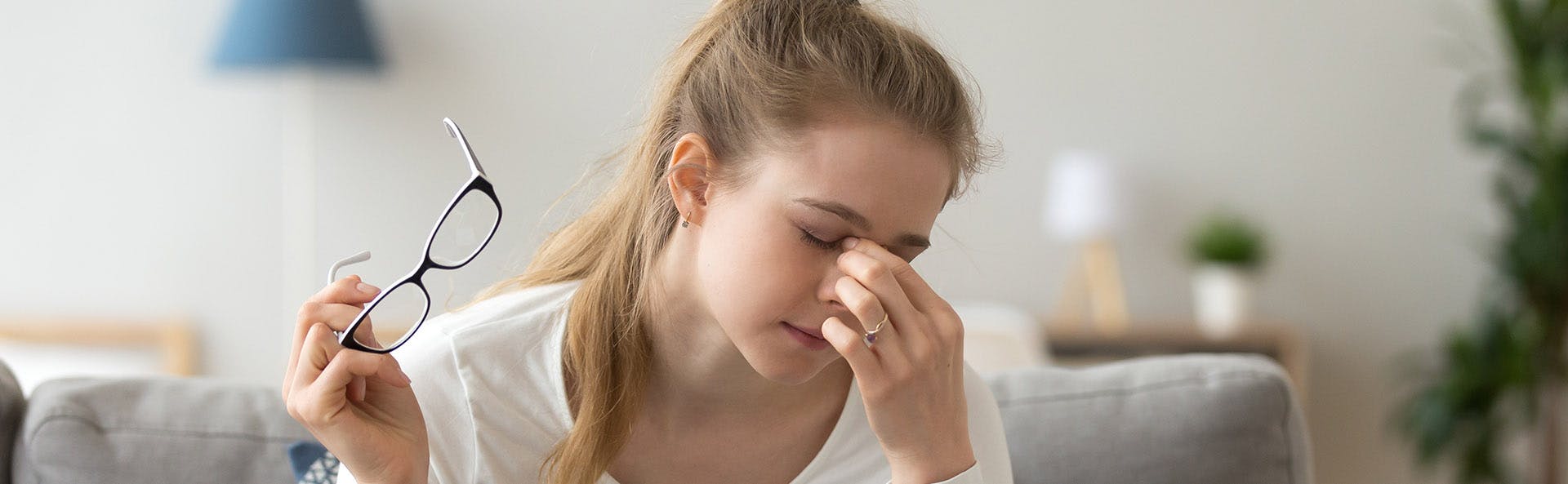 Young woman taking off her glasses and grabbing her nose in pain. Young woman taking off her glasses and grabbing her nose in pain.