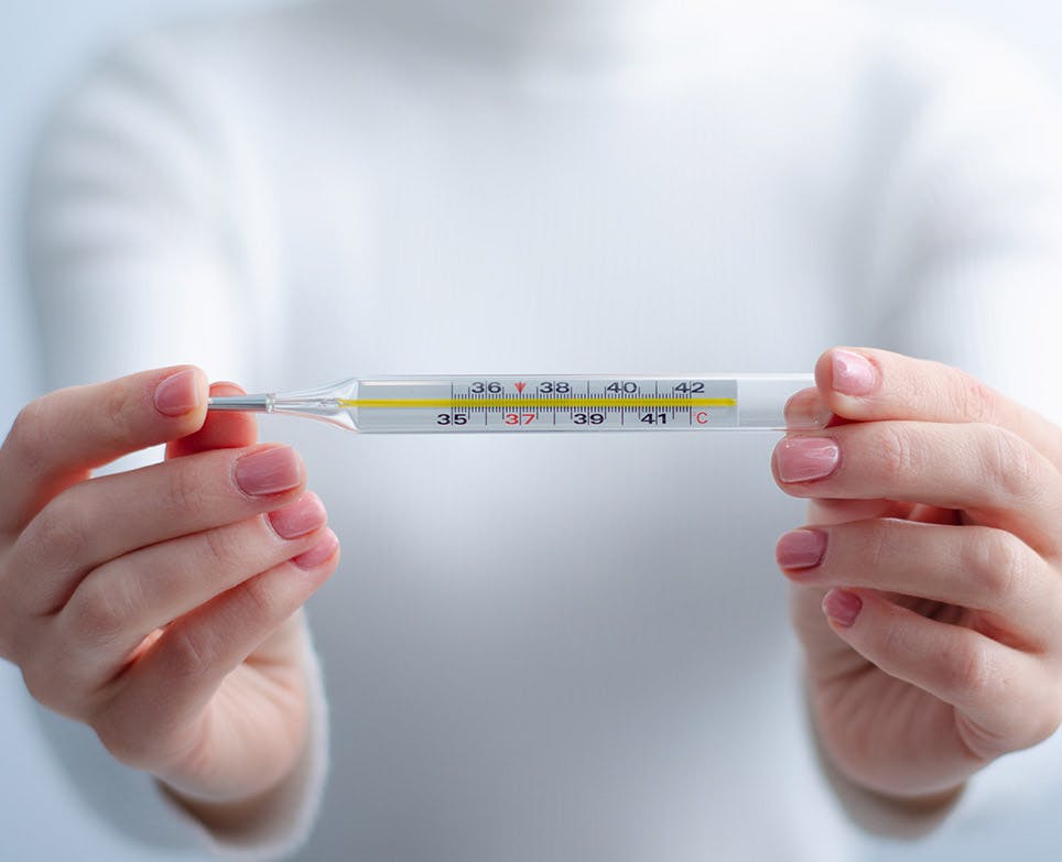 Woman checking and holding a traditional thermometer. Woman checking and holding a traditional thermometer.