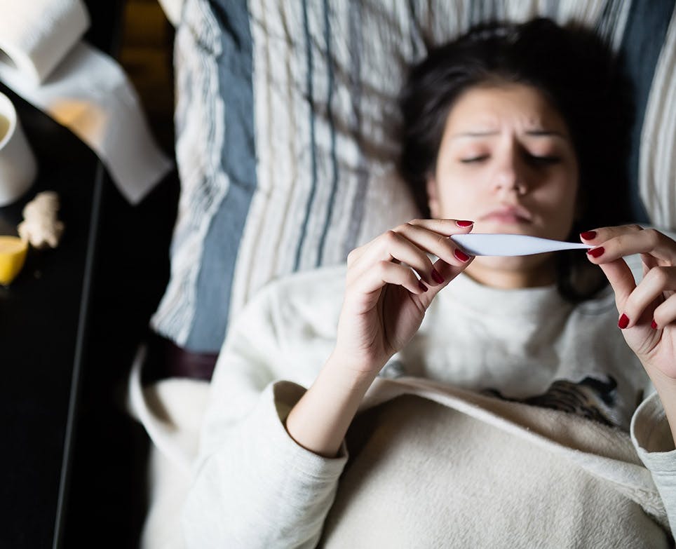 Woman taking her temperature on digital thermometer. Woman taking her temperature on digital thermometer.