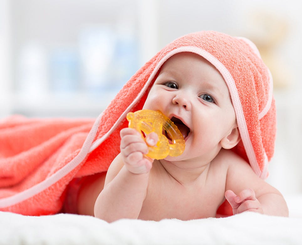 Baby biting a teething toy after a bath. Baby biting a teething toy after a bath.