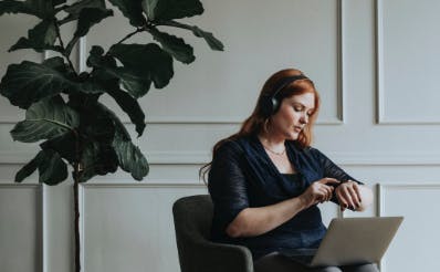 Girl seated, using a laptop with headphones on