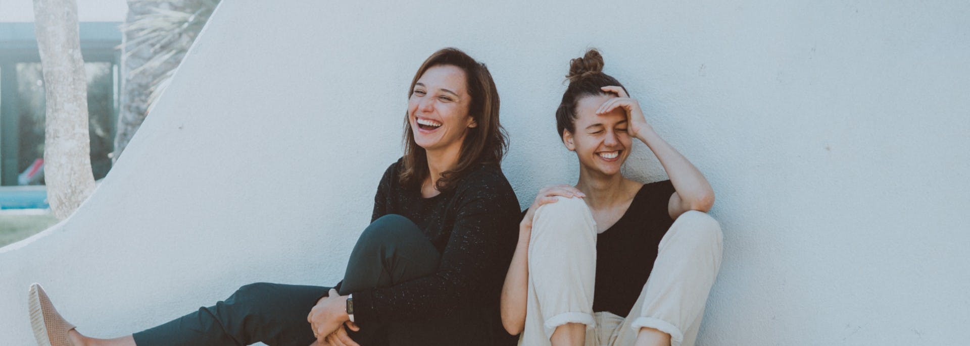 Two girls laughing on white concrete bench