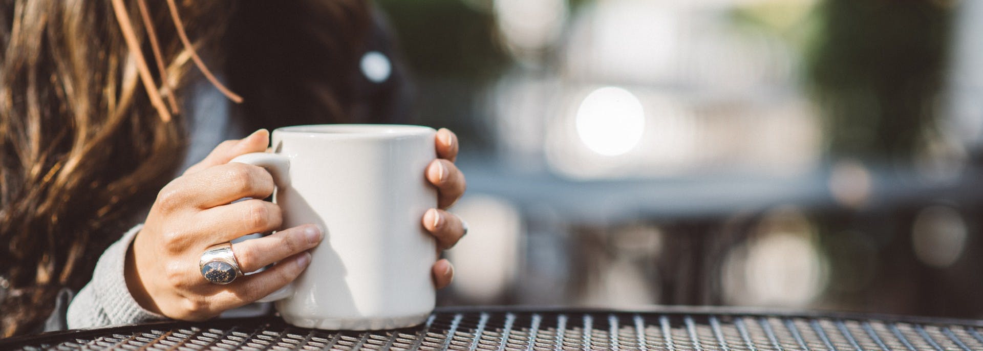 Girls hands holding a cup of coffee on grey table
