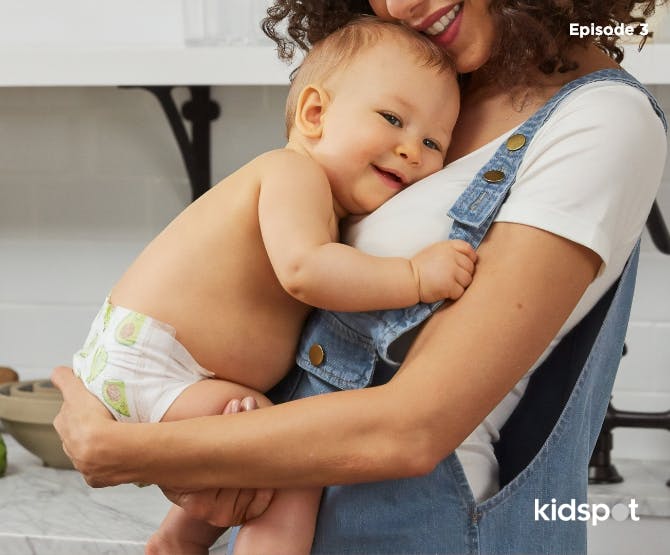 Mother in overalls hugging her baby in nappy