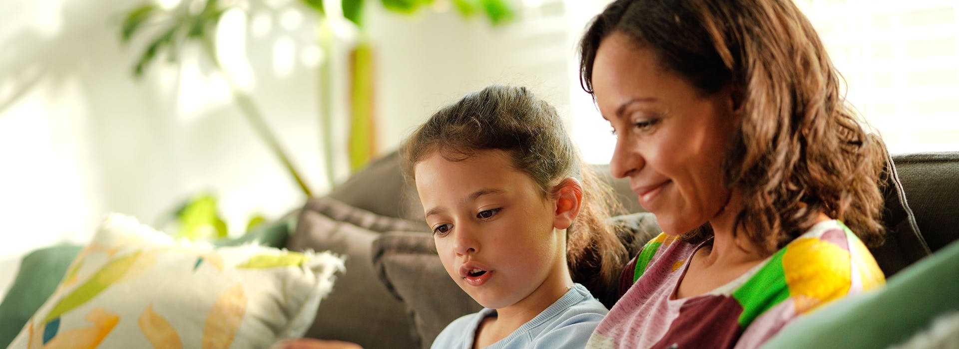 Mum and daughter reading book on couch