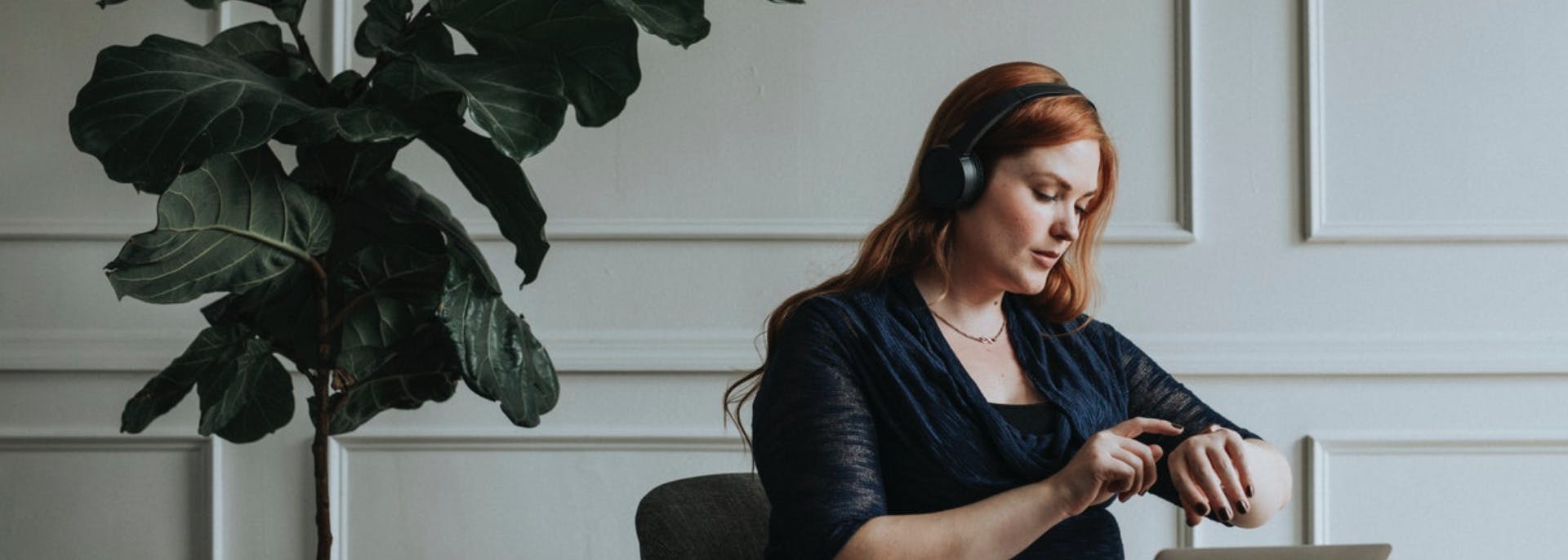 Girl seated, using a laptop with headphones on