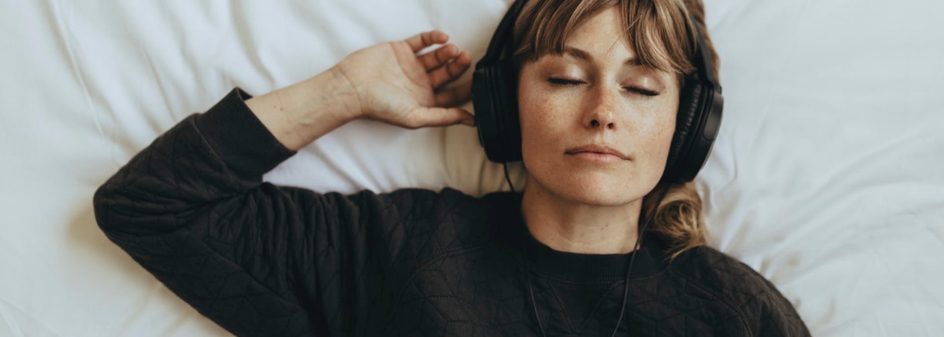 Girl lying on bed with headphones on