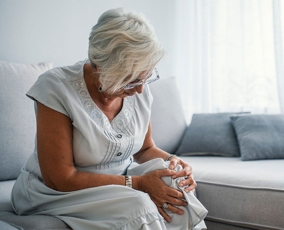 Mujer mayor sujetando su rodilla en señal de dolor. Mujer mayor sujetando su rodilla en señal de dolor.