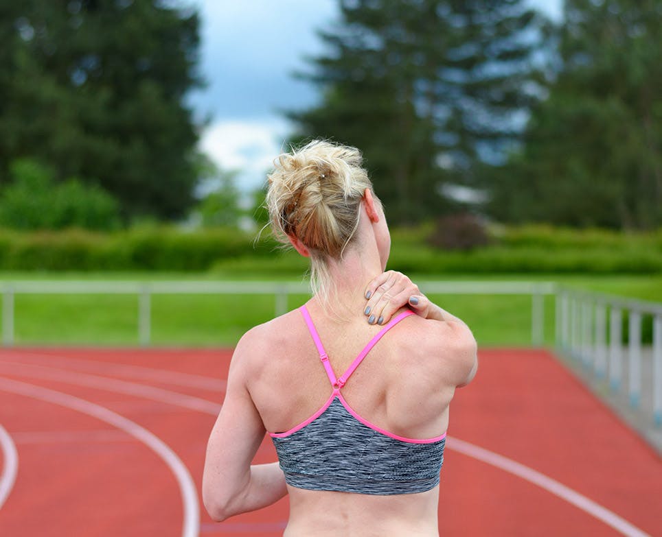 Mujer deportista se toca la aprte de atrás del cuello en señal de dolor. Mujer deportista se toca la aprte de atrás del cuello en señal de dolor.