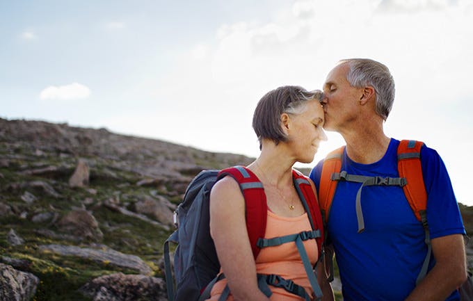 Men kiss woman forehead during a Hikes Along A Mountain Trail Men kiss woman forehead during a Hikes Along A Mountain Trail