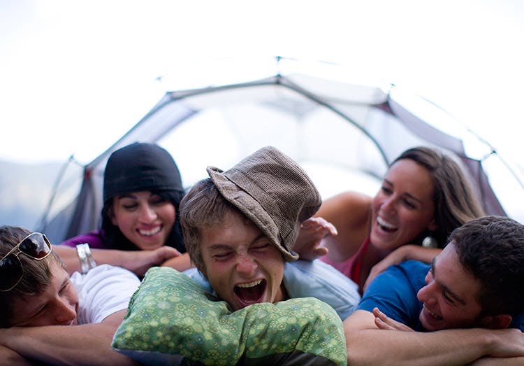 Friends Laugh As They Pile On Top Of Each Other During A Camping Trip Friends Laugh As They Pile On Top Of Each Other During A Camping Trip