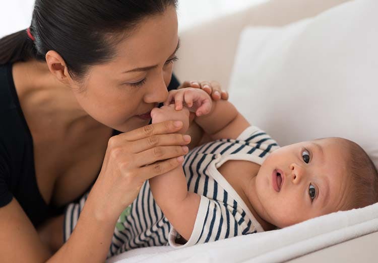 Mom Giving Kiss To Baby On Soft Bed Mom Giving Kiss To Baby On Soft Bed
