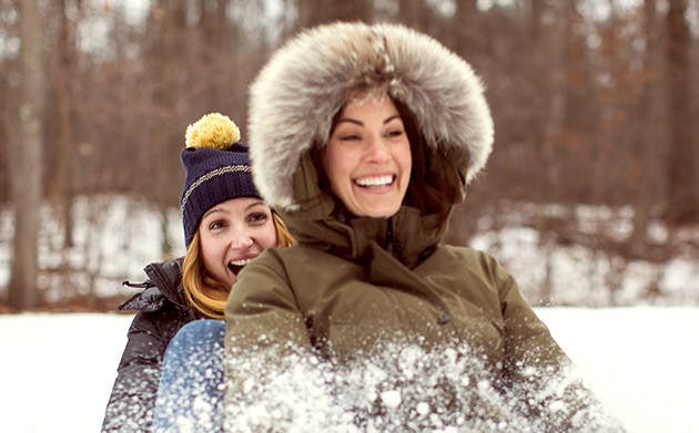 Two Women Having Fun Sledding In Woods Two Women Having Fun Sledding In Woods