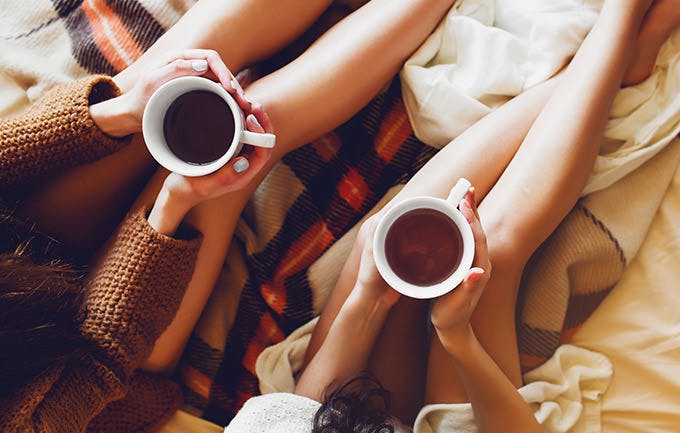 Hai chị em trong phòng ngủ cùng sách cũ và tách cà phê trên tay, mặc áo len ấm Hai chị em trong phòng ngủ cùng sách cũ và tách cà phê trên tay, mặc áo len ấm