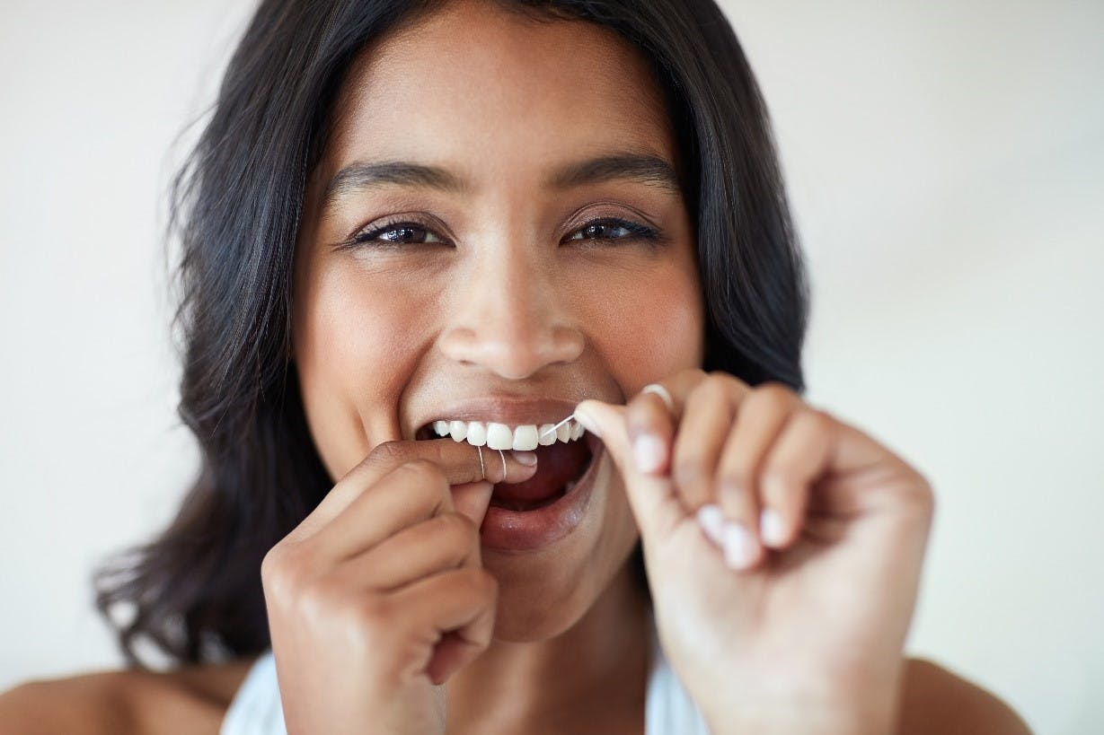 Flossing your teeth woman looking forward flossing her teeth