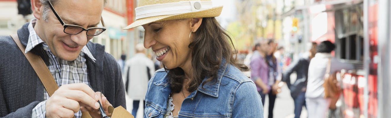 Man and woman smiling on sidewalk of busy street Man and woman smiling on sidewalk of busy street