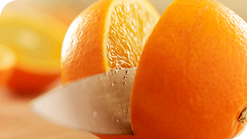 Click here to learn more about acid erosion Fresh orange being sliced in half with a knife