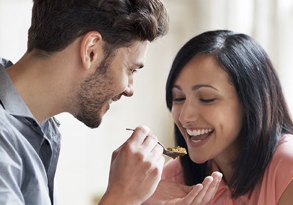 Man sharing his food with a woman from a spoon Man sharing his food with a woman from a spoon
