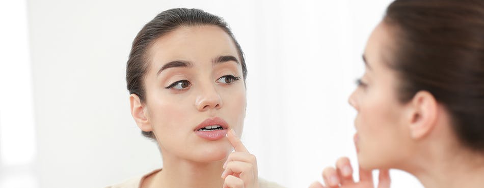 Young woman looking at her lips in the mirror Young woman looking at her lips in the mirror