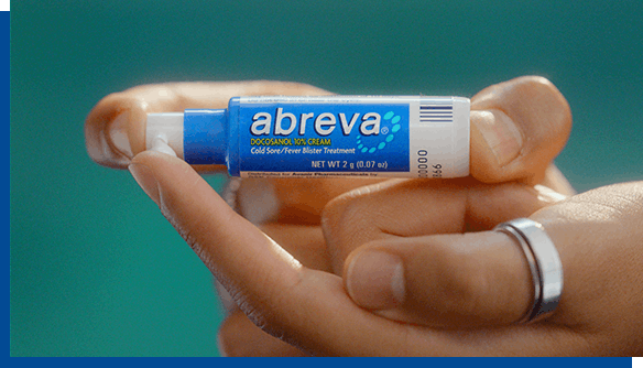 Person with ring on finger holding Abreva Cold Sore Cream pump Person with ring on finger holding Abreva Cold Sore Cream pump