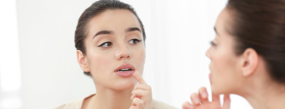 Young woman looking at her lips in the mirror Young woman looking at her lips in the mirror