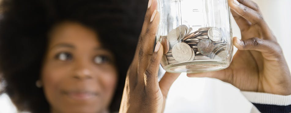 Femme tenant un bocal de monnaie | Suivez la règle des 50/30/20 Femme tenant un bocal de monnaie | Suivez la règle des 50/30/20