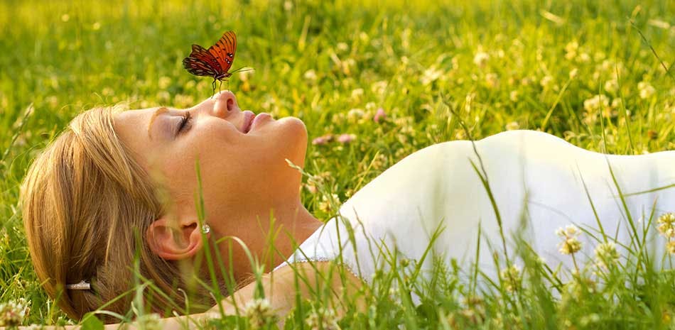Une femme étendue dans l'herbe, un papillon posé sur le nez Une femme étendue dans l'herbe, un papillon posé sur le nez